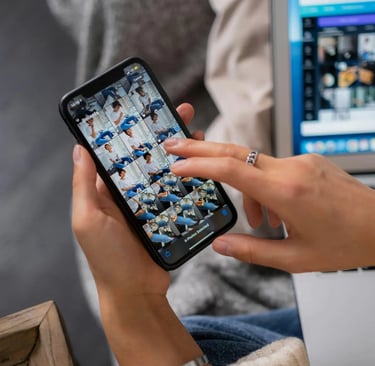 Person selecting photos on a smartphone screen next to a laptop for mobile content creation.