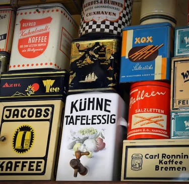 Collection of vintage coffee and snack tins with retro German branding on a shelf.