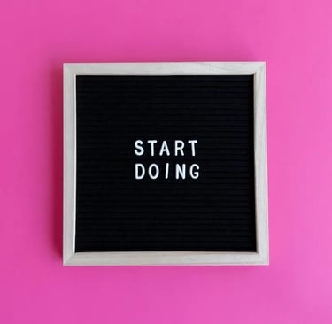 Inspirational black letter board with Start Doing message on a vibrant pink background.