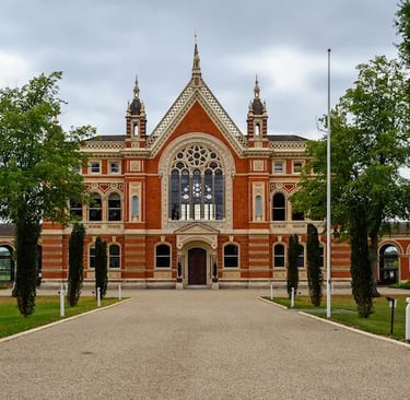 Gothic Revival architecture of Dulwich College red brick building with green trees and gravel path.