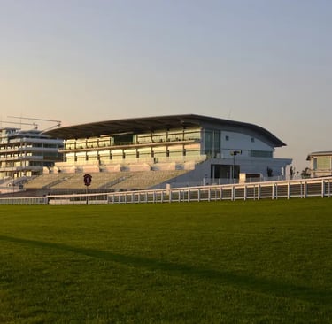 Epsom racing grandstand and green turf track at sunset.