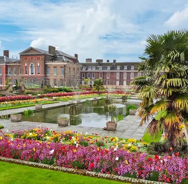 Kensington Palace sunken garden featuring colorful flower beds, a reflective pond, and palm trees.