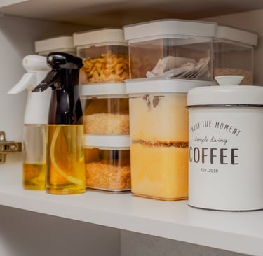Kitchen cupboard with full storage canisters, oil spray bottles and beige coffee canister