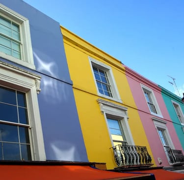 Brightly colored pastel houses along Portobello Road in Notting Hill, London, under a clear blue sky.
