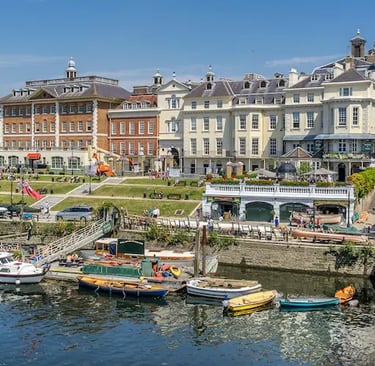 Historic waterfront buildings and colorful boats docked along the River Thames in Richmond, London.