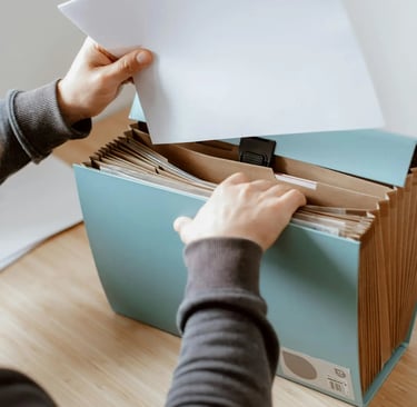 Person organizing paperwork in a blue expanding file folder for office document storage.