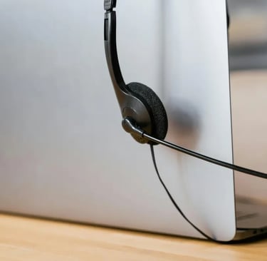 Professional call center headset with microphone resting on a silver laptop for remote work support.