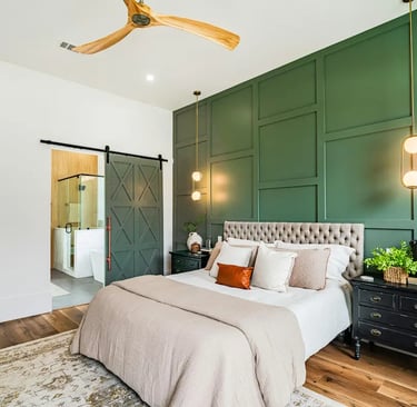 Modern bedroom with dark green board and batten accent wall, tufted headboard, and sliding barn door.