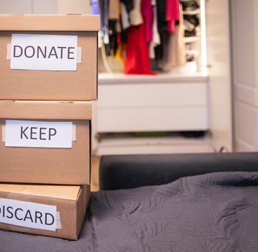 Stacked cardboard boxes labelled donate, keep, and discard for home organisation and decluttering.