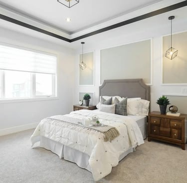 Modern master bedroom with a grey upholstered headboard, white bedding, and geometric pendant lights.