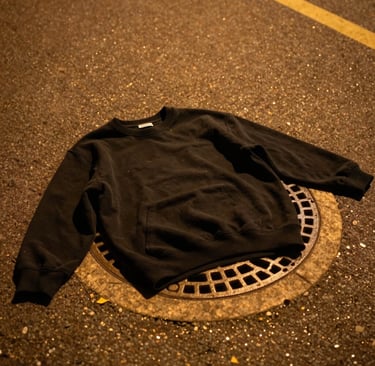 Side view of a black snapback hat with international orange embroidery, boldly standing out on a concrete ledge