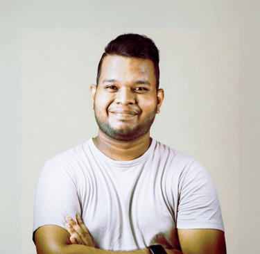 Smiling man with folded arms wearing a light shirt in front of a neutral background