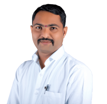 Professional portrait of an Indian man with a mustache wearing a white collared shirt against a black background.