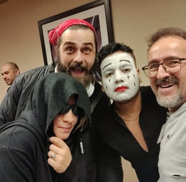 A diverse group of friends in creative costumes, including white face paint makeup and a hooded cloak.