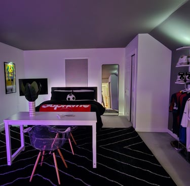 Modern bedroom featuring LED ambient lighting, a sneaker display shelf, and a white desk with clear chairs.