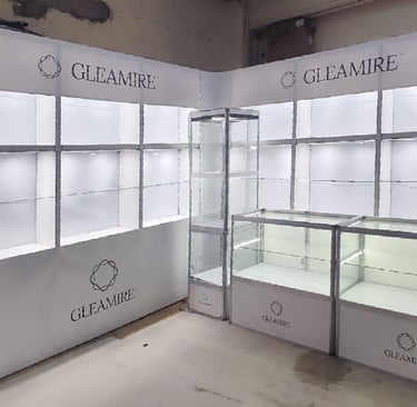 Custom GLEAMIRE branded jewelry display showcases and white backlit shelving units for retail exhibitions.