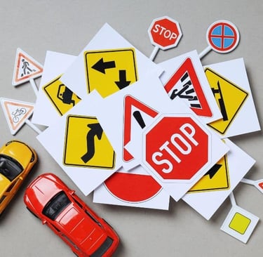 a yellow and a red toy car, a bunch of small road signs icons laying on the ground