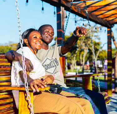 a romantic couple sitting together on a bench at the park