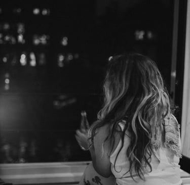 A woman looking out of the window thinking about her ex and wondering if she should reach out to him