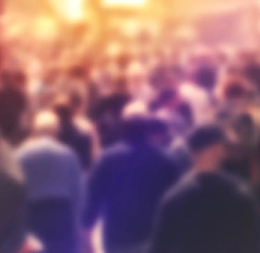An very diffuse image with a crowd of people walking on a city street.