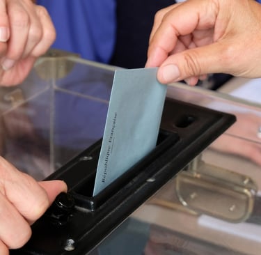 Photo d'une enveloppe glissée dans une urne évoquant le vote et l'élection