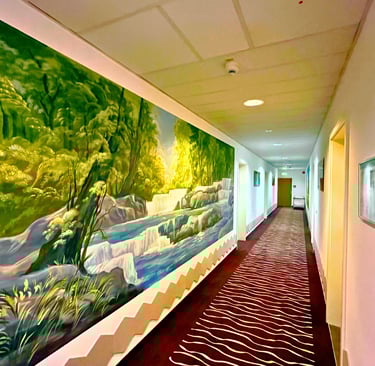 A long hallway with a large nature mural of a waterfall and green forest on the wall.