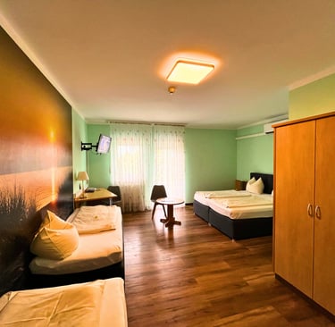 Modern hotel room with twin beds, sunset wall mural, wooden floors, and a spacious wardrobe.