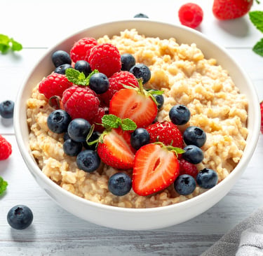 A healthy bowl of oatmeal topped with fresh strawberries, blueberries, and raspberries.