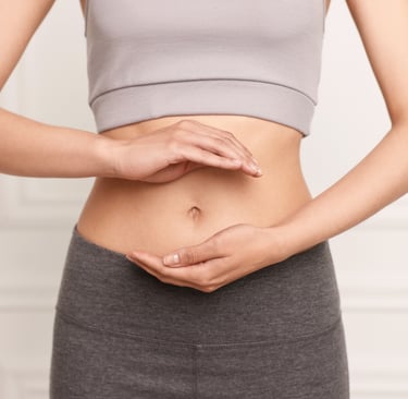Woman in yoga wear holding her hands over her stomach to symbolize digestive health and gut wellness.