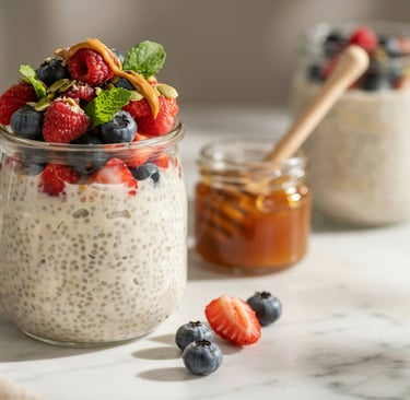 Healthy overnight chia seed pudding in a glass jar topped with fresh raspberries, blueberries, and honey.