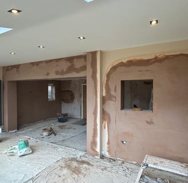 Freshly applied brown plaster on interior walls during a home renovation project with recessed lighting.