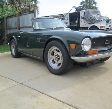 A green convertible Triumph TR6 classic British sports car.