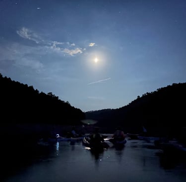 conjunto de piraguas a la luz de la luna en mitad del embalse de la Toba con montañas a contraluz