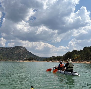 Piragua remando en el embalse de la Toba con un cielo nuboso precioso y montañas y vegetacion al fon