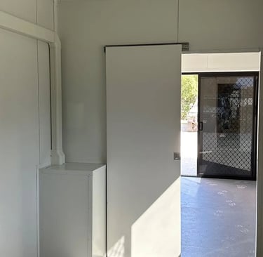 Interior of a modern white modular cabin featuring a sliding door and a security mesh screen door.