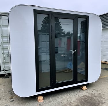 A white modern prefab backyard office pod with black glass doors and rounded corners.