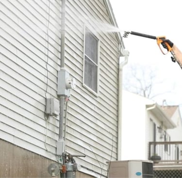 A man pressure washing a house.