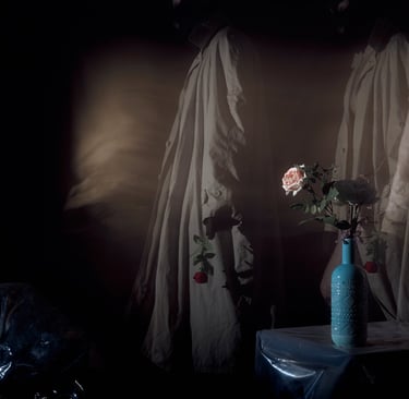 Surreal art piece featuring shadowy figures in trench coats near a blue vase with roses.