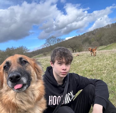 Cheeky German Shepherd with tongue out, sat next to a teenage boy