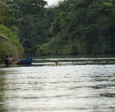 Local fisherman checking on the fish trap while the boy enjoys swimming