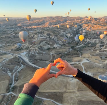 a group of hot air balloons flying over a valley in summer