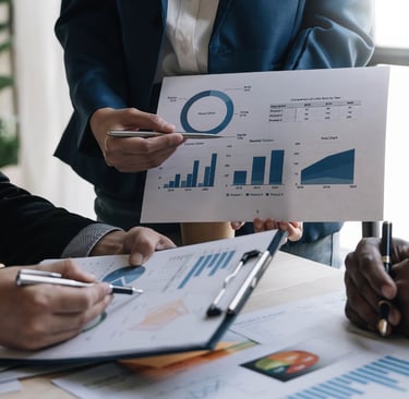 Business team reviewing financial data charts and sales reports in a corporate office meeting.