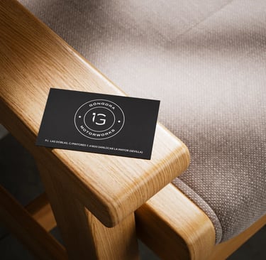 Tarjeta de visita de Góngora Motorworks sobre el brazo de madera de una silla