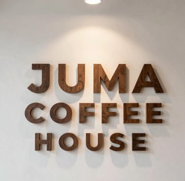 Happy customer savoring a latte inside the inviting, sunlit Juma Coffee House.