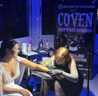 Novia recibiendo un tatuaje real en su boda, mientras el stand ofrece tattoos en vivo para invitados