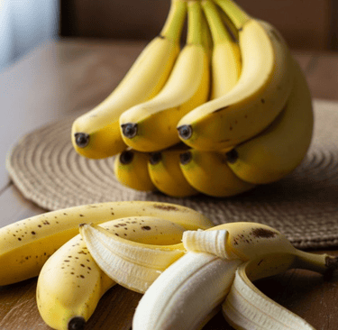 Fresh ripe yellow bananas and a peeled banana on a wooden table with a natural background.