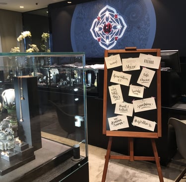 Luxury jewelry store interior with glass display cases and a wooden easel featuring calligraphy signs.