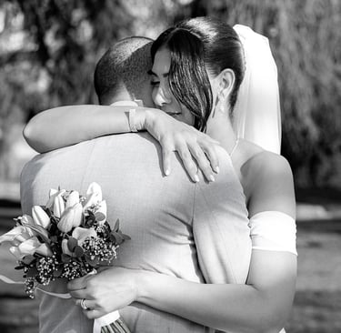 Photo en noir et blanc d'une mariée tenant un bouquet et enlaçant son époux lors d'un mariage en ple