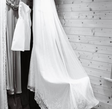 Élégant long voile de mariée blanc bordé de dentelle, drapé sur une chaise dans un dressing rustique