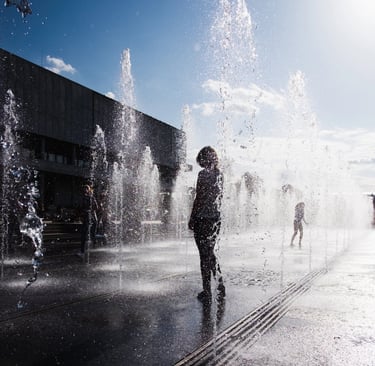 Silhouetted Girl standing in fountain in summer
